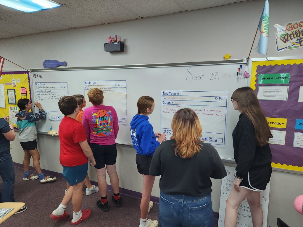 Students writing mock professional emails in groups.