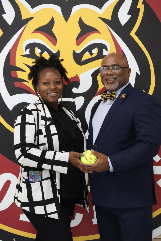 woman and man holding softball with bobcat in background