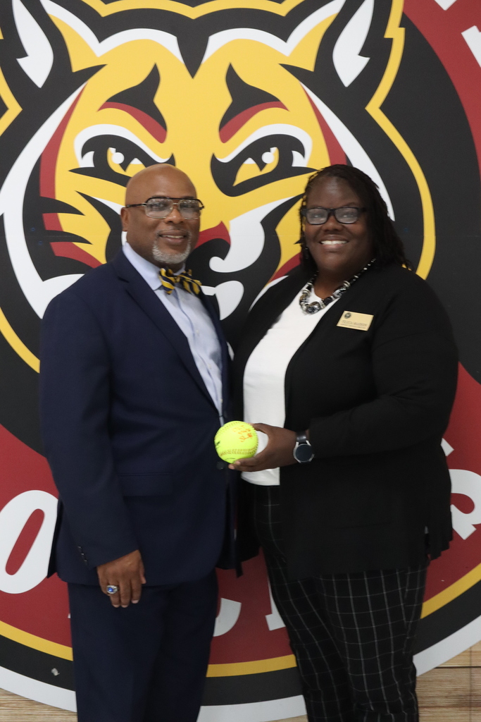 man and woman holding a softball with bobcat in the background