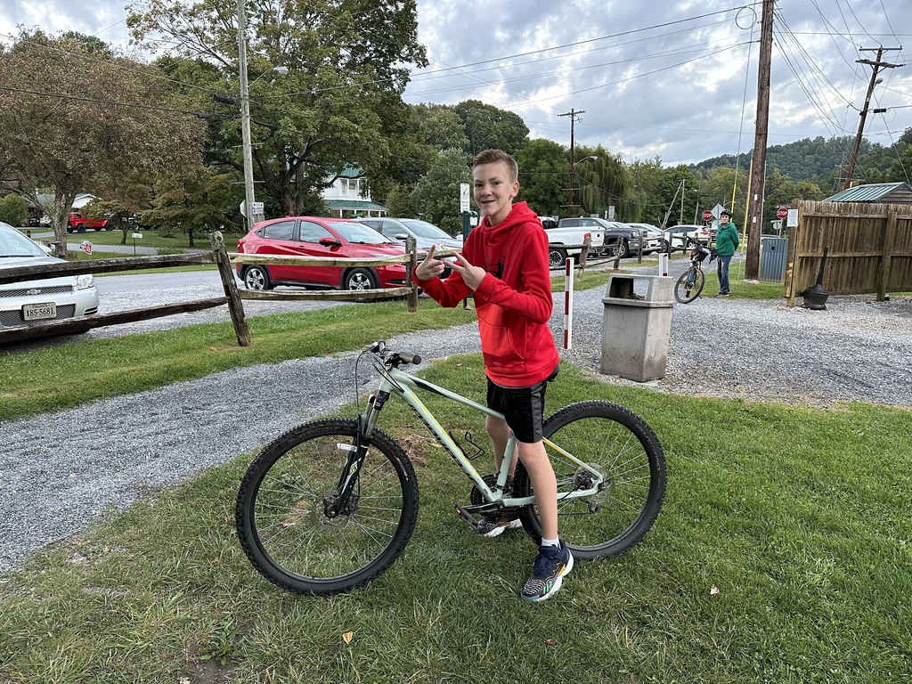 A boy stands with his bicycle.