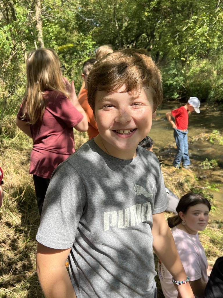 A boy stands near a creek.