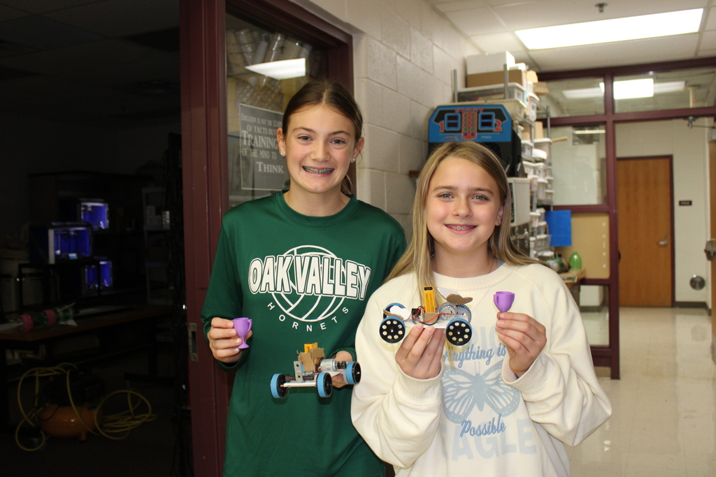 2 girls hold trophies with cars