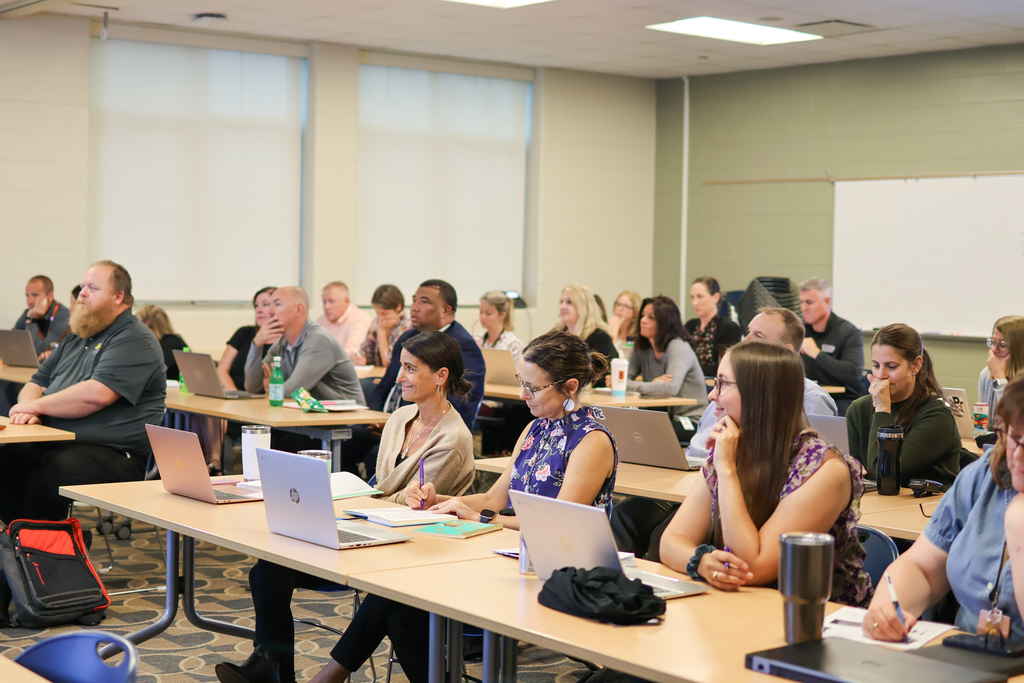a group of people sit at desks in a classroom