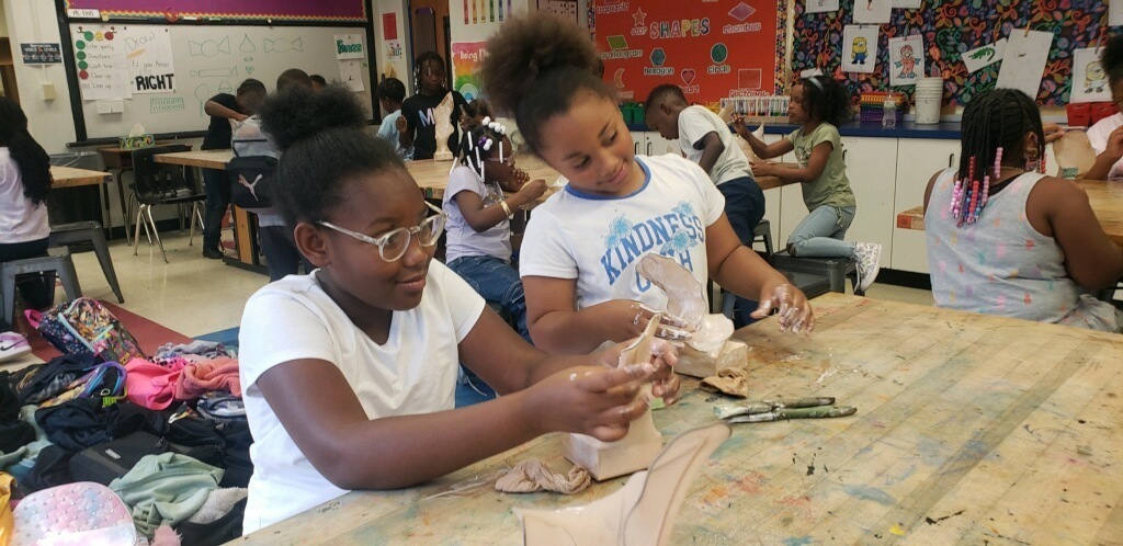 Two students work on sculpting and painting their projects.