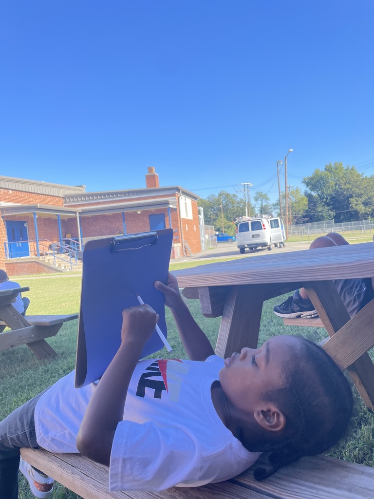 Student draws on a clipboard while looking at the sky.