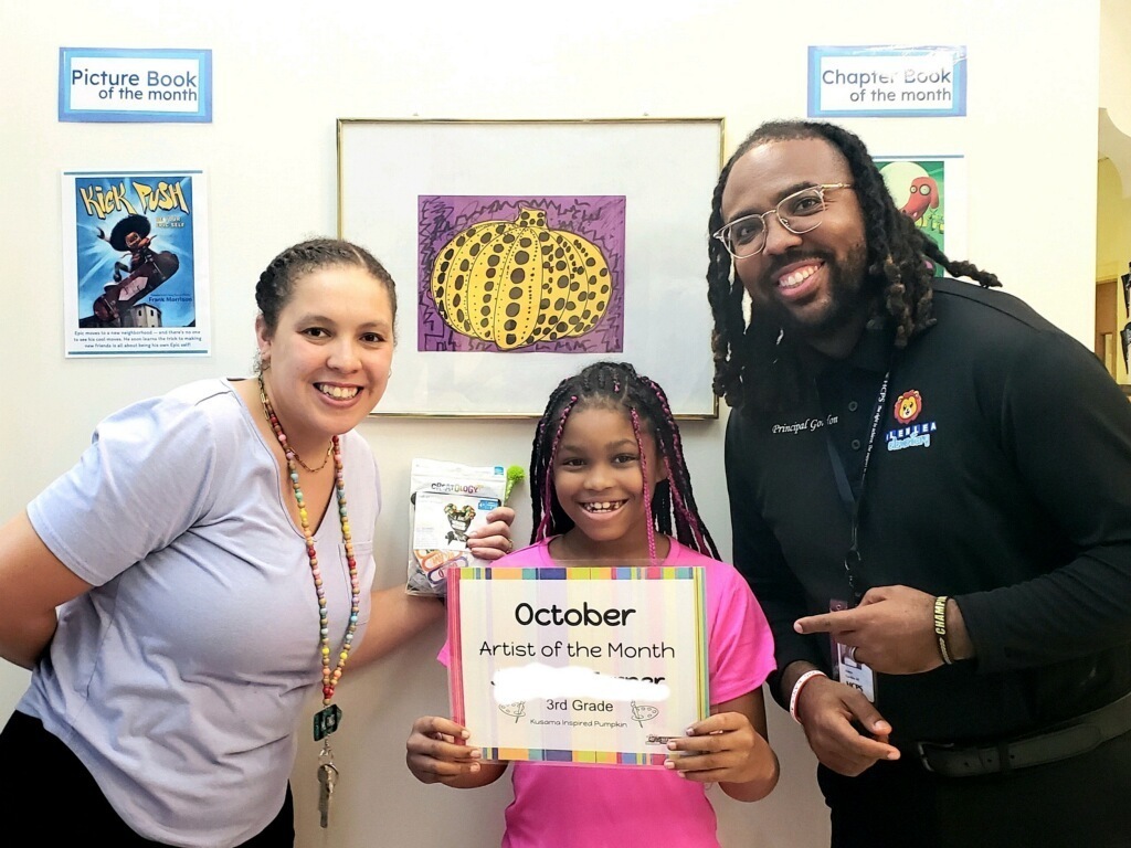 3rd grade student stands with Principal Gordon & Ms. Fines to celebrate being October Artist of the Month
