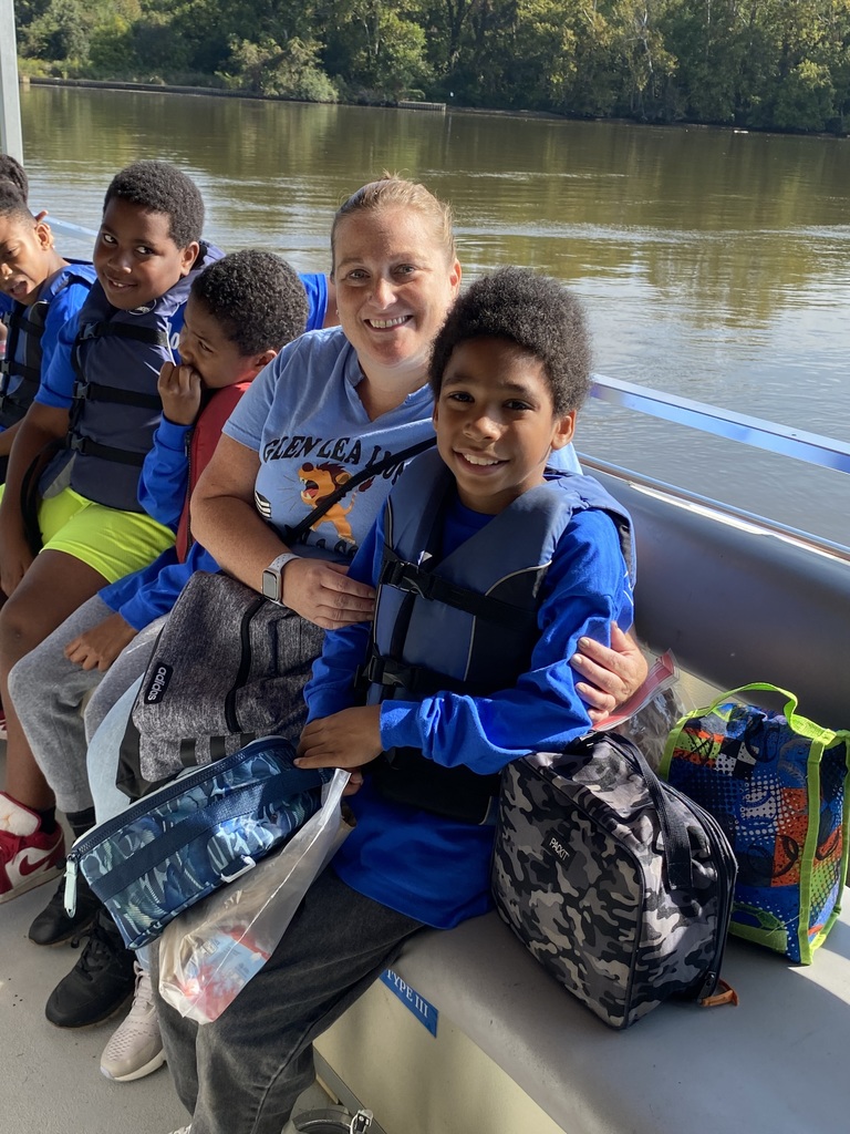 Fourth graders and Ms. Leo sit on the boat bench while on the James.