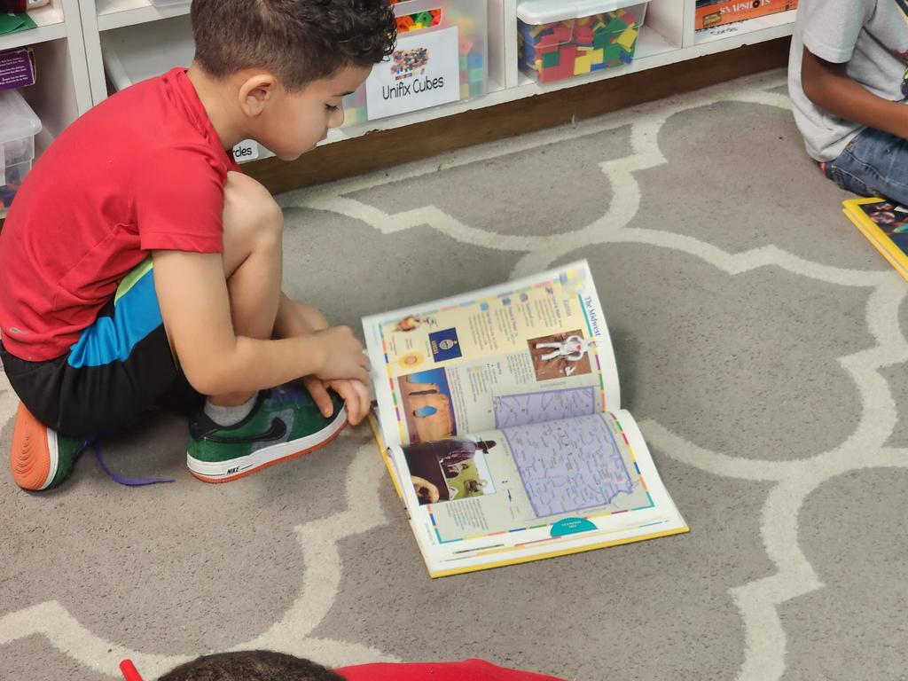 One student browses an atlas of different places.