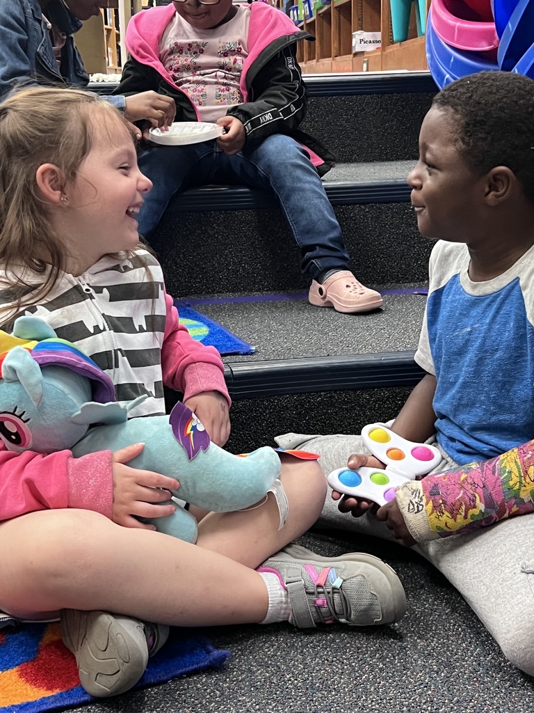Two kindergarteners turn to each other with big smiles.