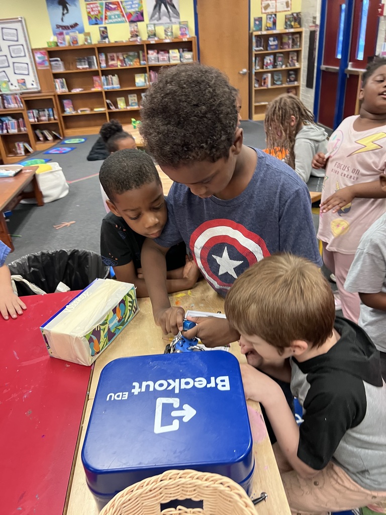 Three second grade students attempt to put the lock code in.