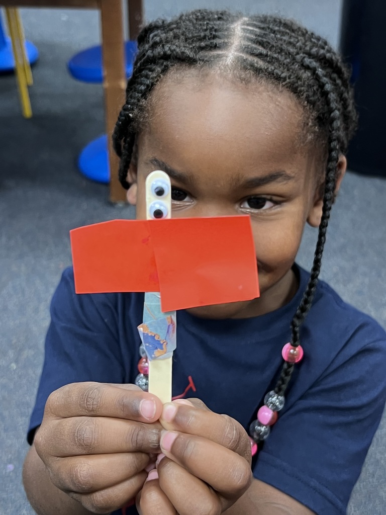 A kindergarten student holds up the butterfly she designed independently.