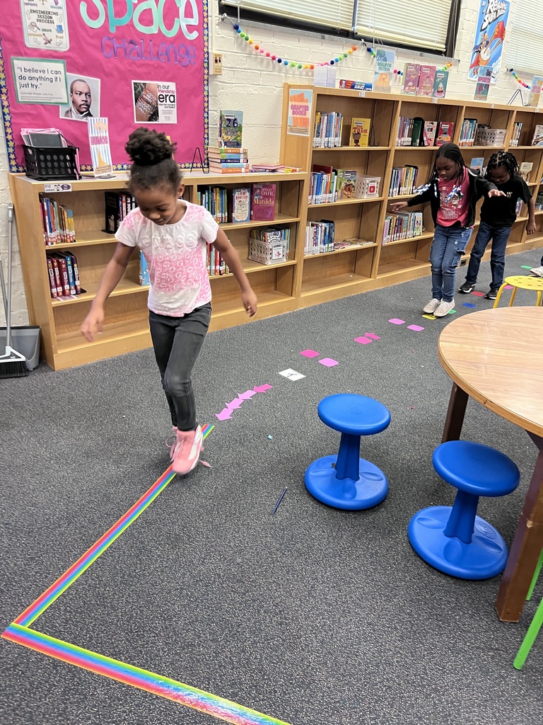 Three 2nd grade students try out the new sensory path in the library.