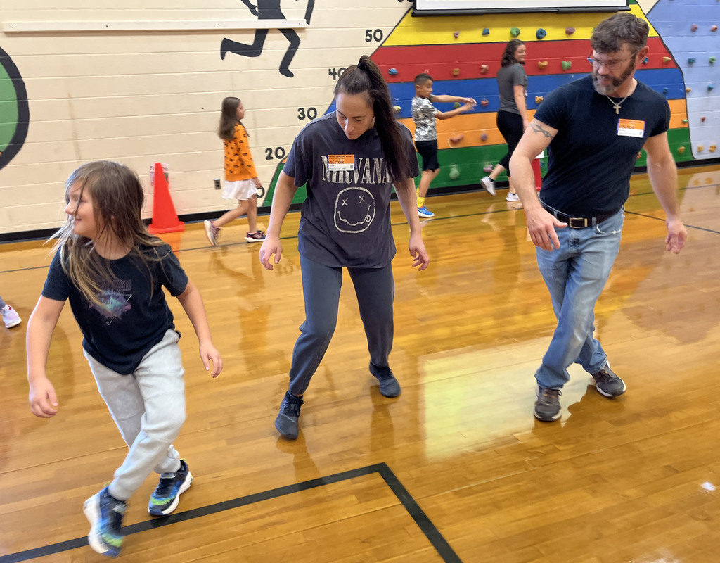 Parents and children participate in PE class in a gym