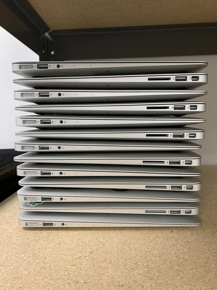 stack of 13 MacBooks on a desk
