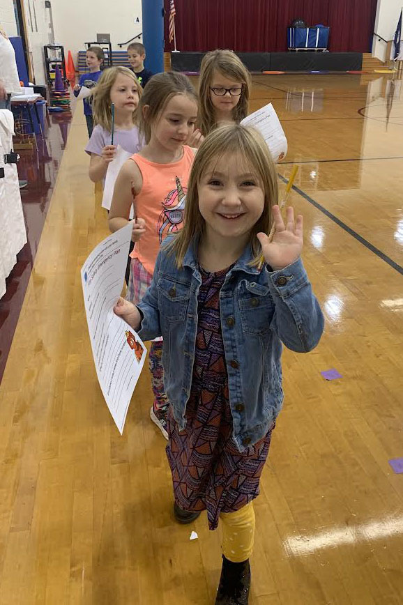 A line of children stand in a gym.
