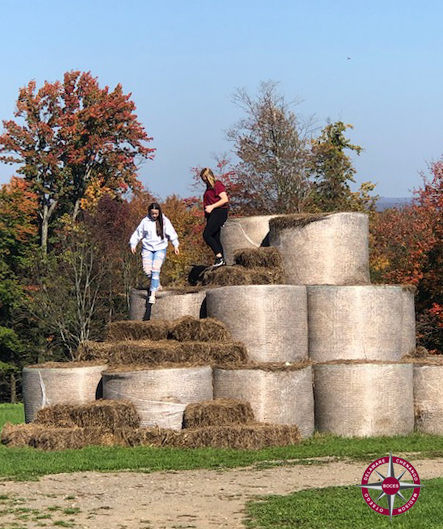 students climb on hay bales