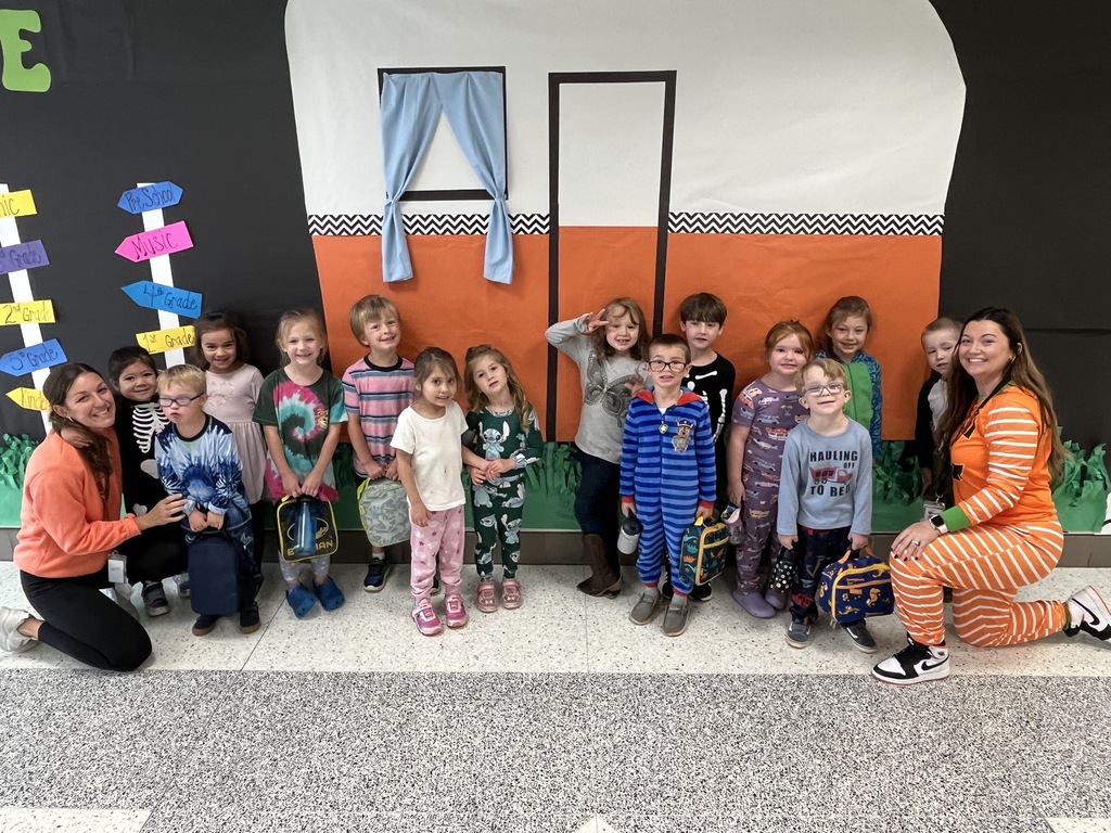 Two adults and a group of children in pajamas pose for a photo.