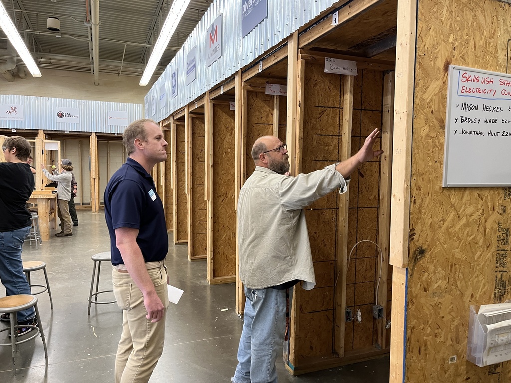 One man shows the electricity classroom tools to another man.