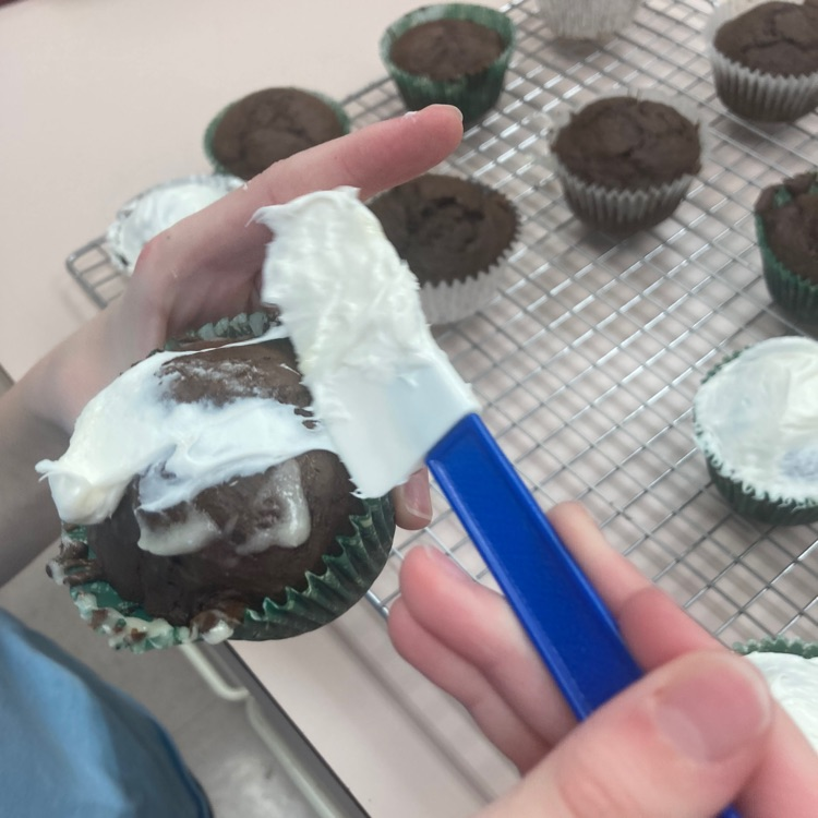 A student frosts a cupcake