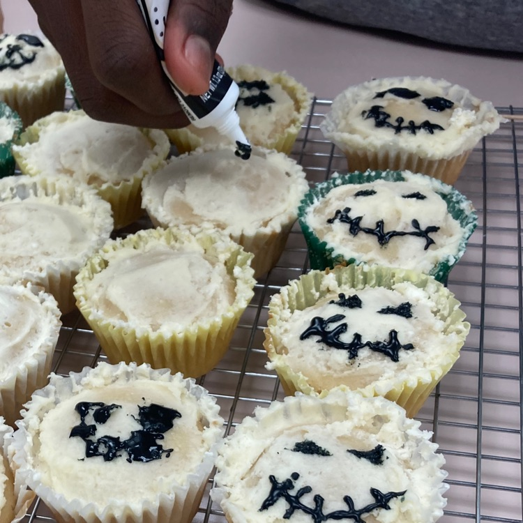 A student ices the frosted cupcakes.