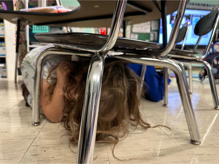 students take cover under desks for an earthquake drill