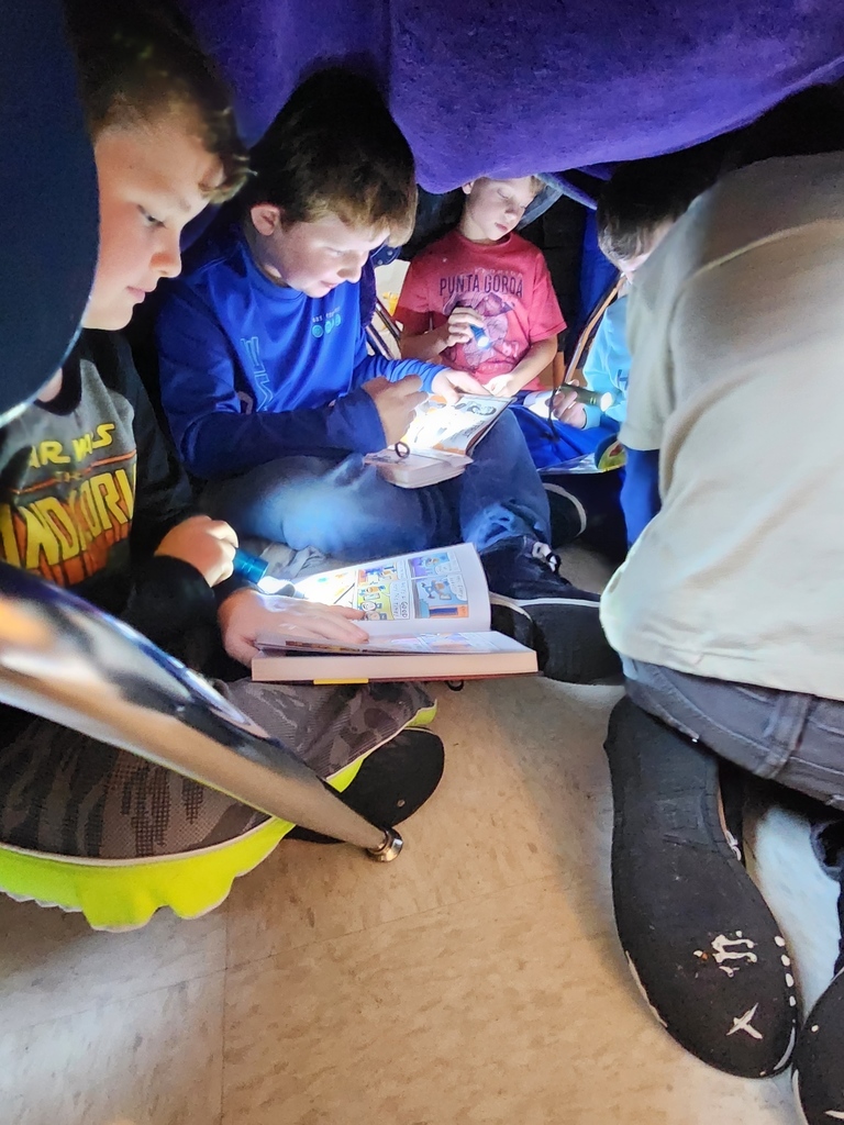 Children read in a blanket fort.