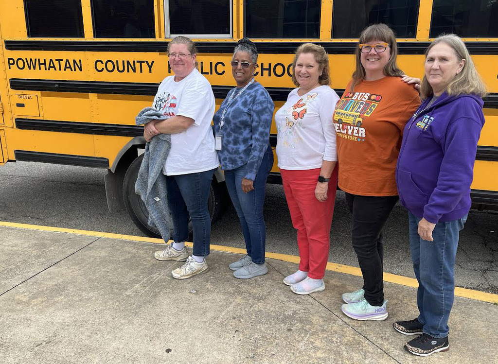 A group of people stands in front of a school bus.