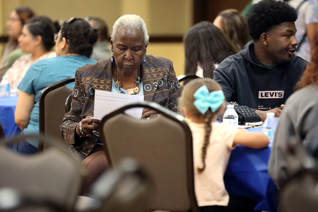 Woman seated at table reads handout