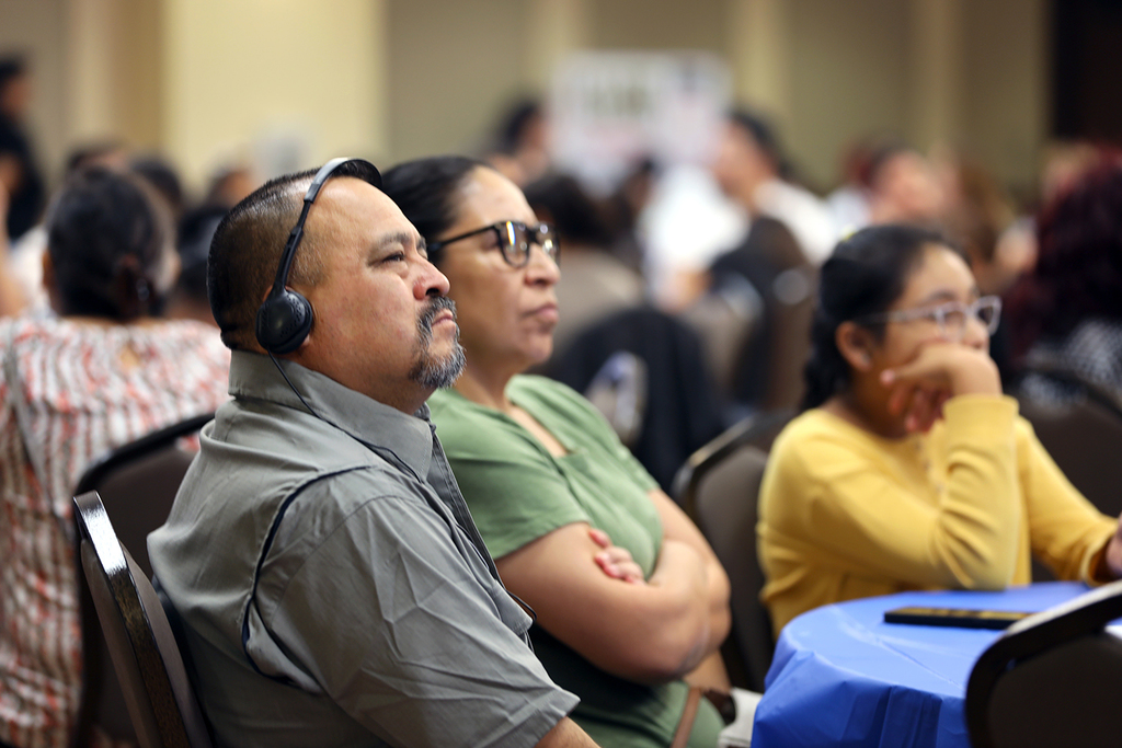 Man in headphones, woman and little girl listen to presentation