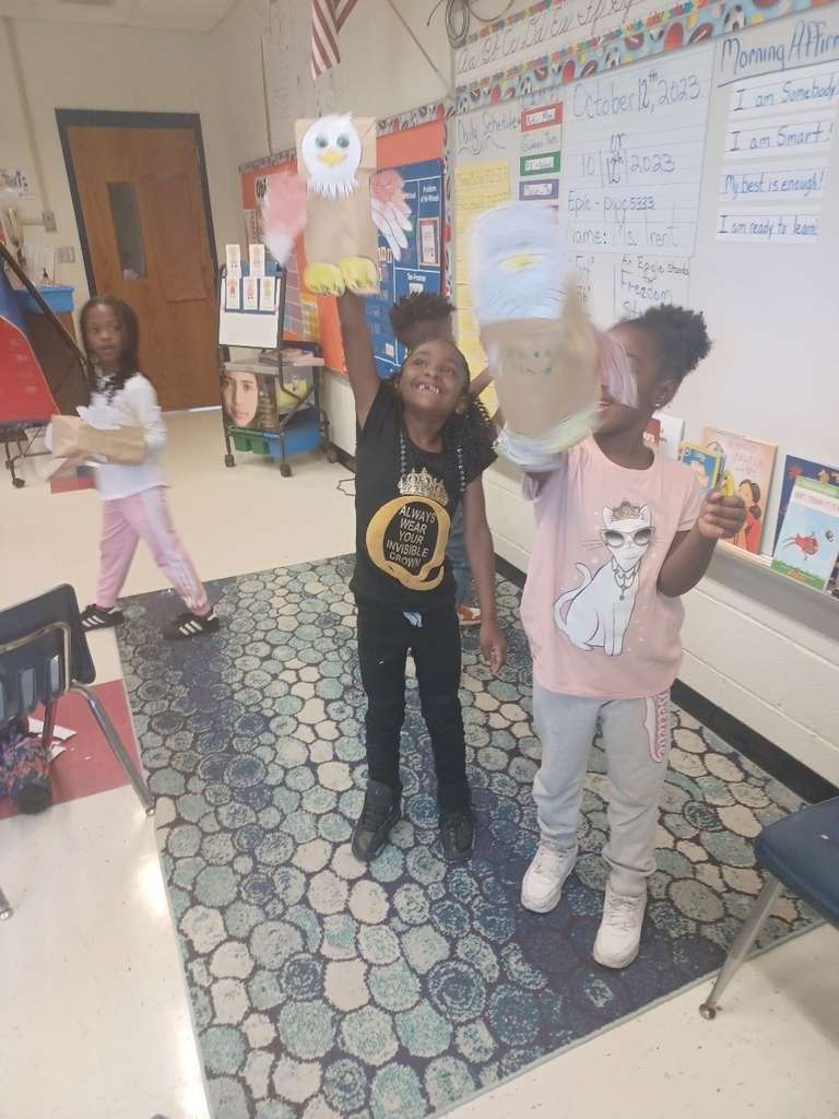 2 first graders smile as they hold up their eagles