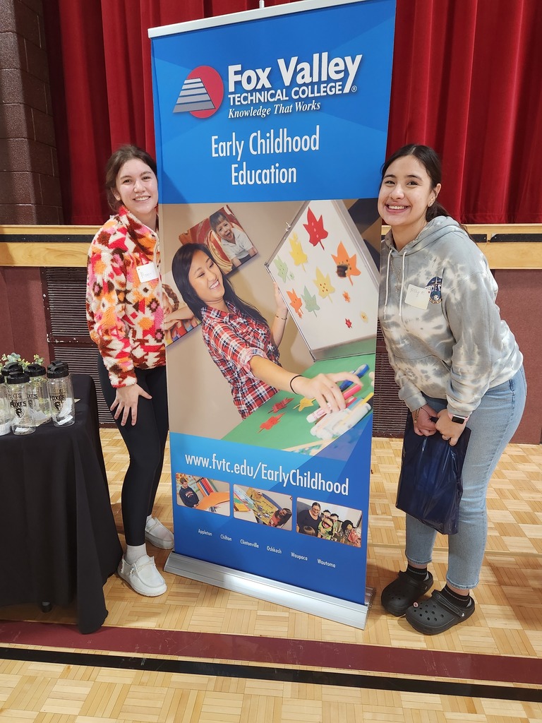 Two students posing near a banner.