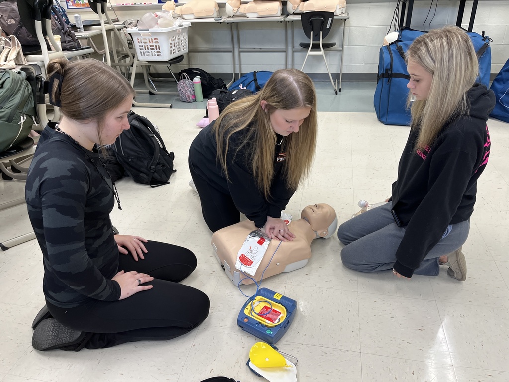 Three students learn to administer CPR.