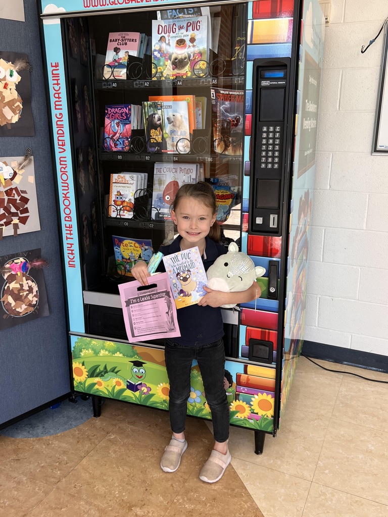 Student standing in front of book vending machine holding prizes