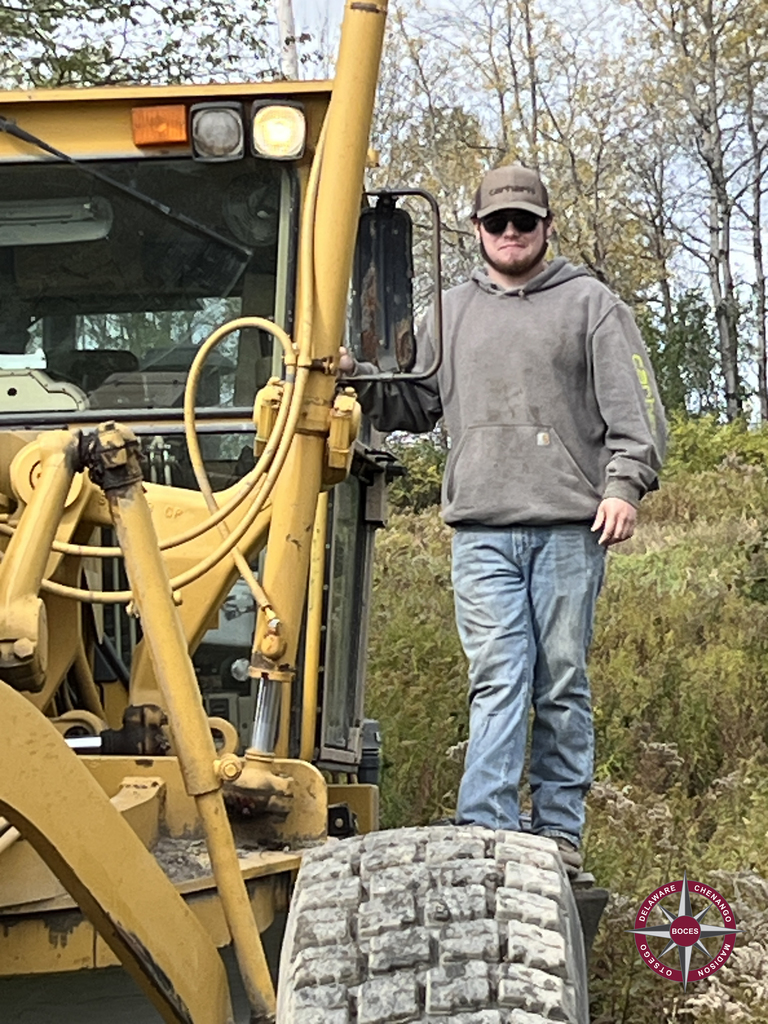 student standing on heavy highway equipment