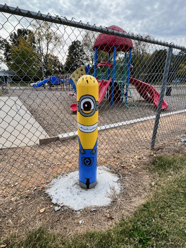 a yellow bollard on the playground has been transformed into a minion 