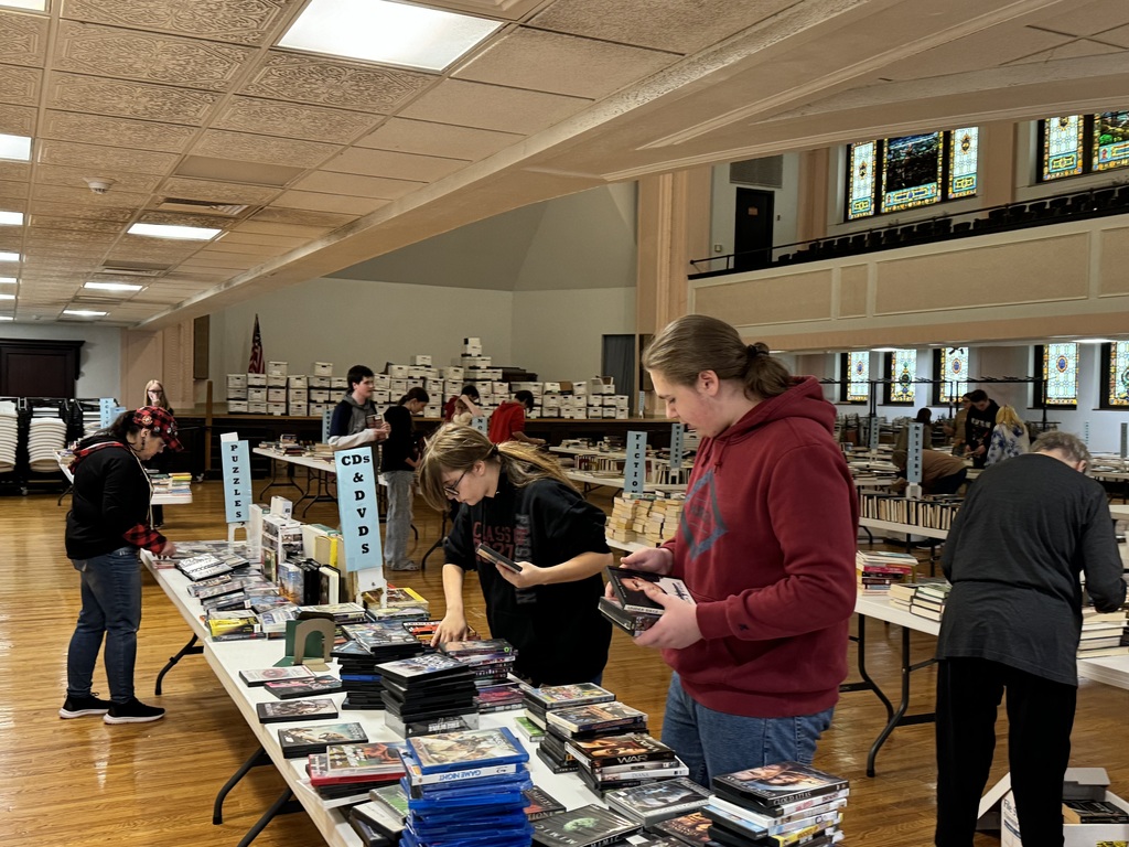 Two students sort through books on a table