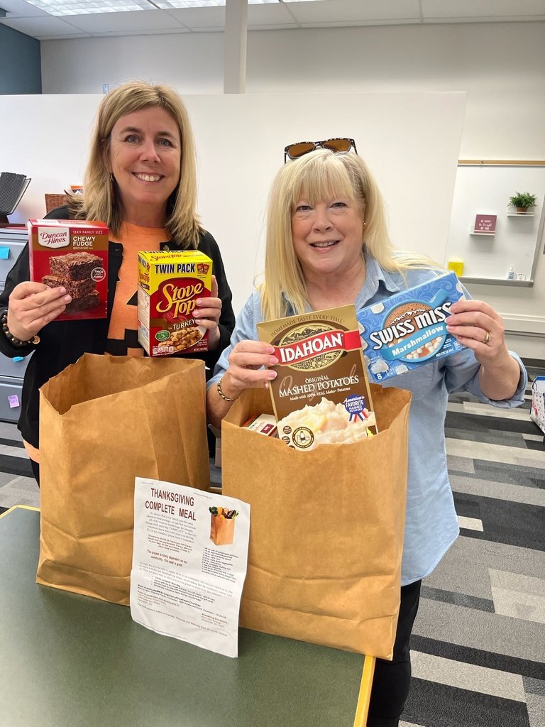 Two women hold up groceries and smile.