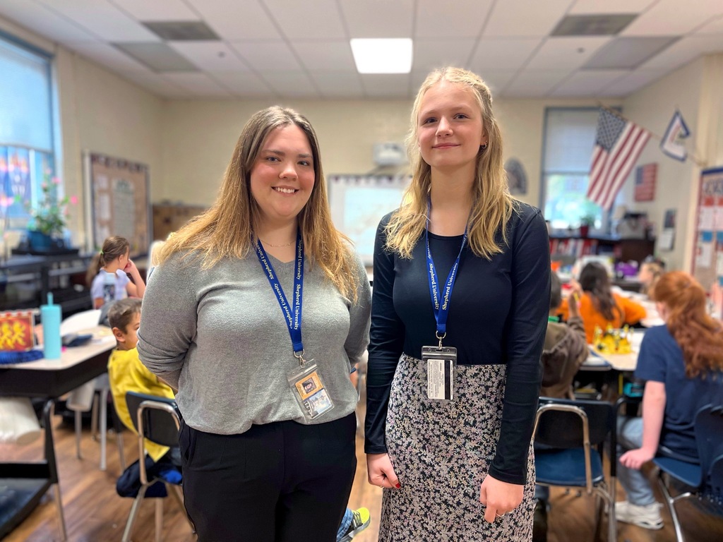 Two female students standing in front of an elementary class