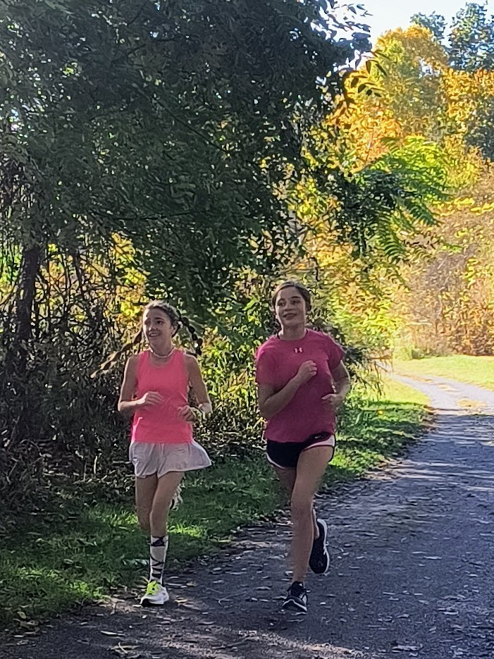 Two girls run on a trail.