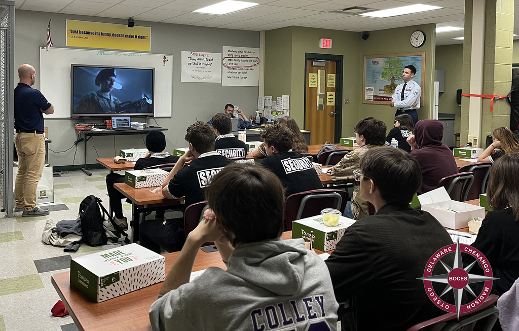 Two Air Force recruiters watch a recruiting film with students in classroom