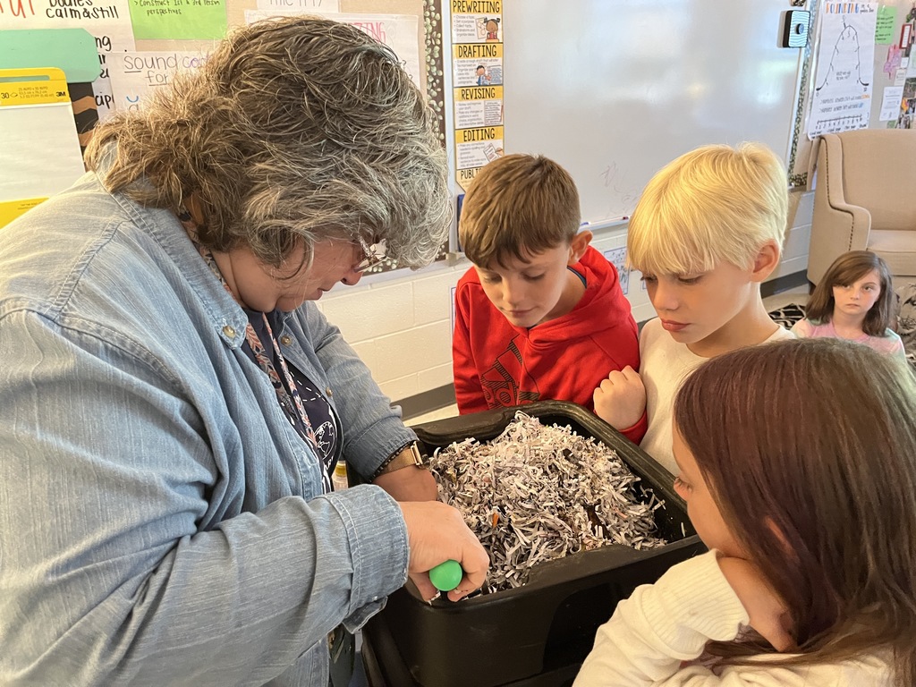 An adult shows students how worm composting works.