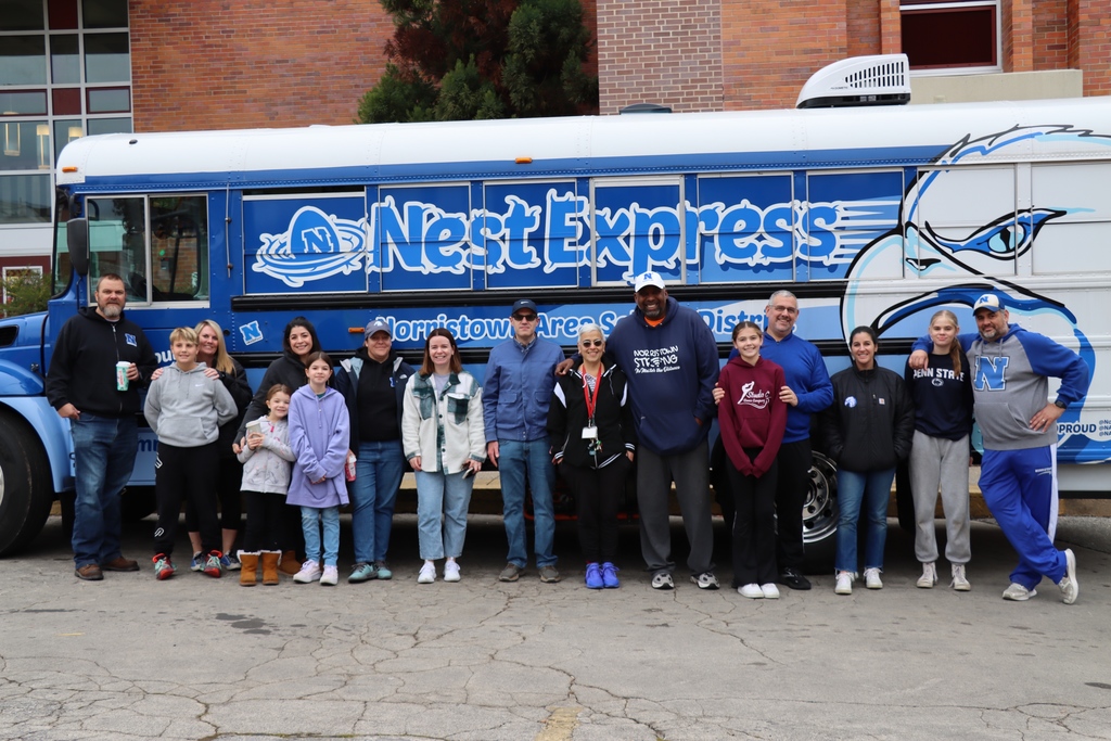 NASD Staff and Conicelli partners standing in front of NASD's Nest Express Bus. El personal de NASD y los socios de Conicelli parados frente al autobús Nest Express de NASD.