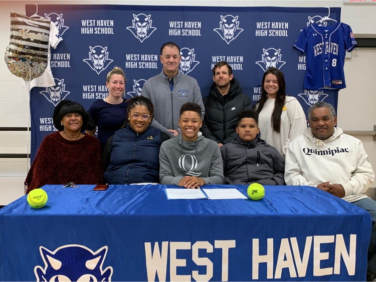 student posing with family and coaching staff