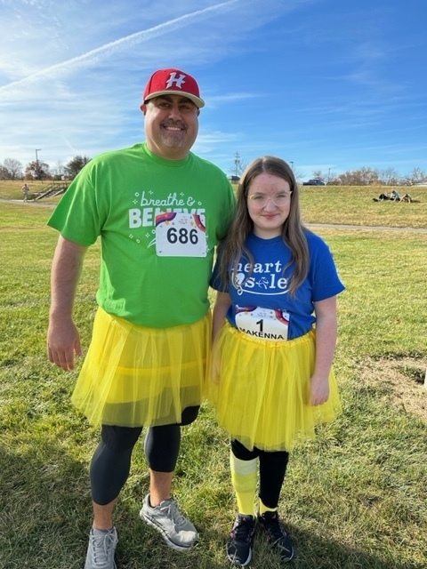 A man stands with a girl in a field.