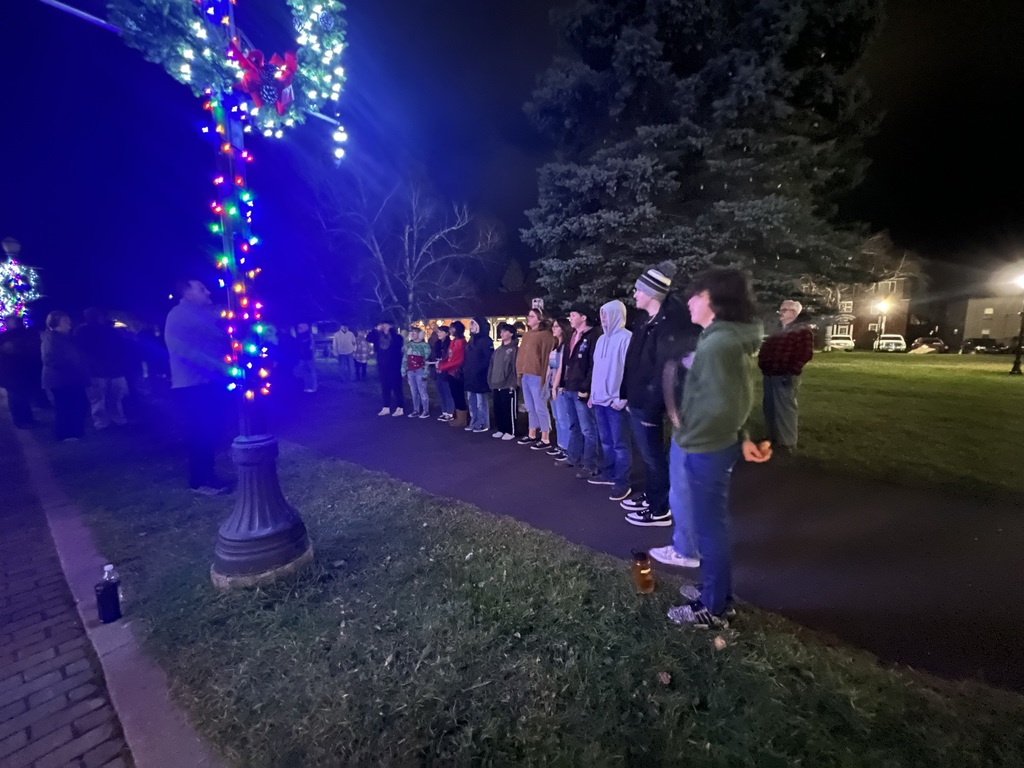 Accent sings Christmas carols in front of a tree