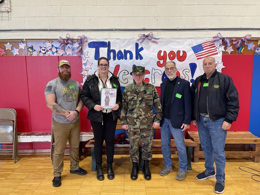 5 Fair Lawn Veterans standing in the school gymnasium in front of a THANK YOU VETERANS poster