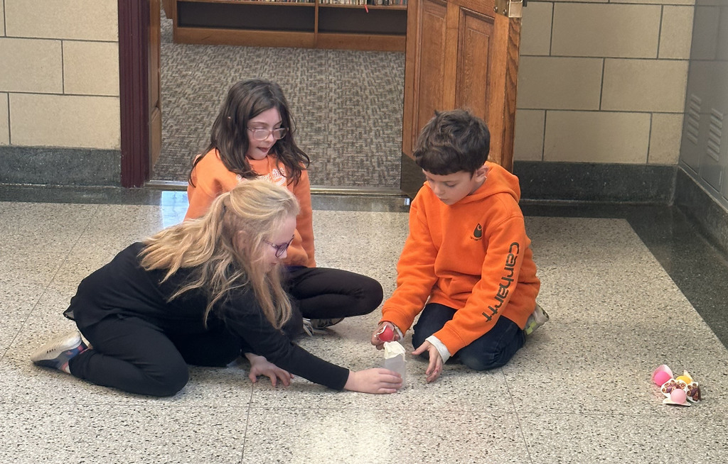 Three students set up a "turkey launcher" a spoon catapult with a paper turkey, in a hallway