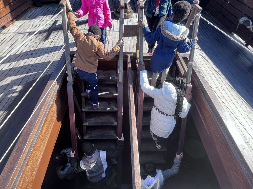 students climbing down ladders to get to the bottom of the ship