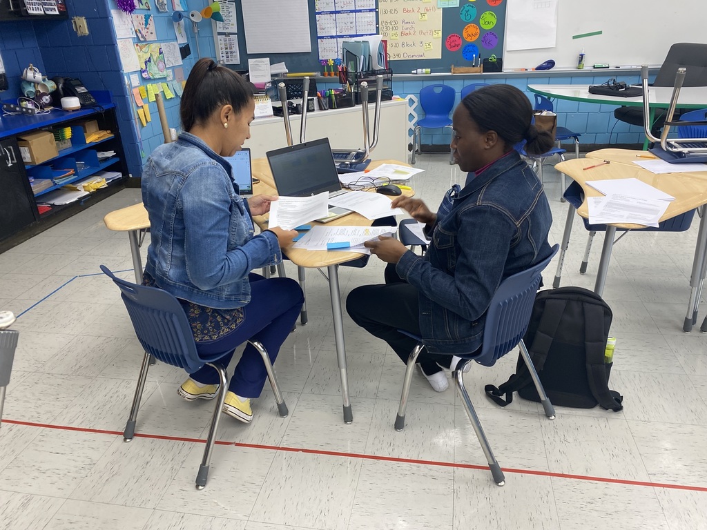 Two teachers working at student desks