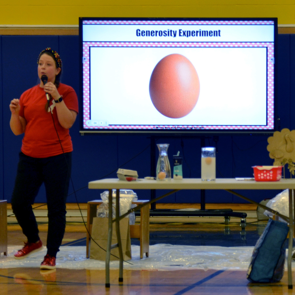 Mrs. Burgess conducts an experiment showing an egg sink in unsalted water and float in salted water, with salt representing generosity and how being generous to others can help our peers "rise to the top"